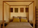 lit à baldaquin en teck couette avec 2 oreillers couleur taupe et 2 oreillers kaki à pompons multicolores
